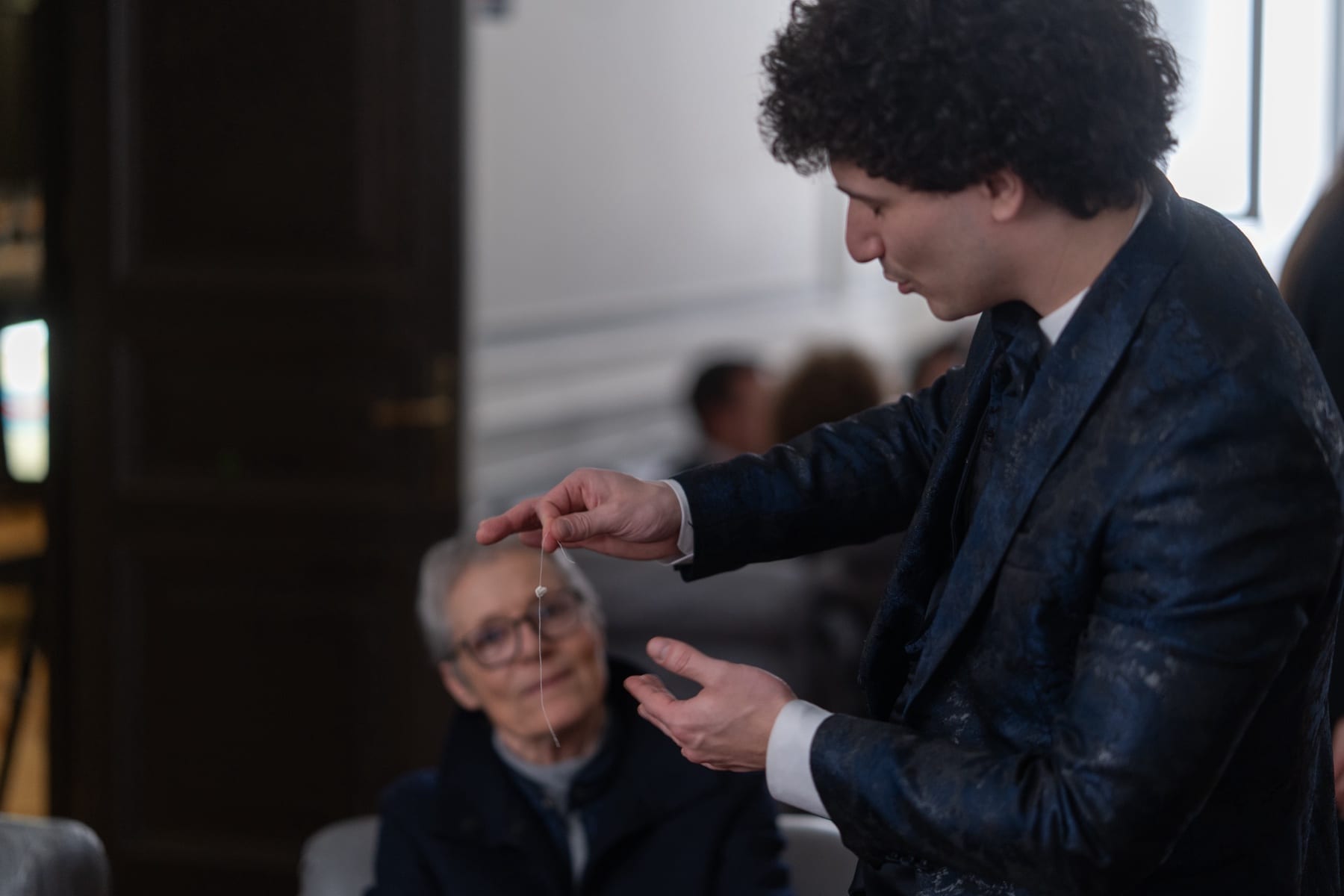 Matteo Angrisano fa oscillare un pendolo davanti a una spettatrice durante un numero di mentalismo