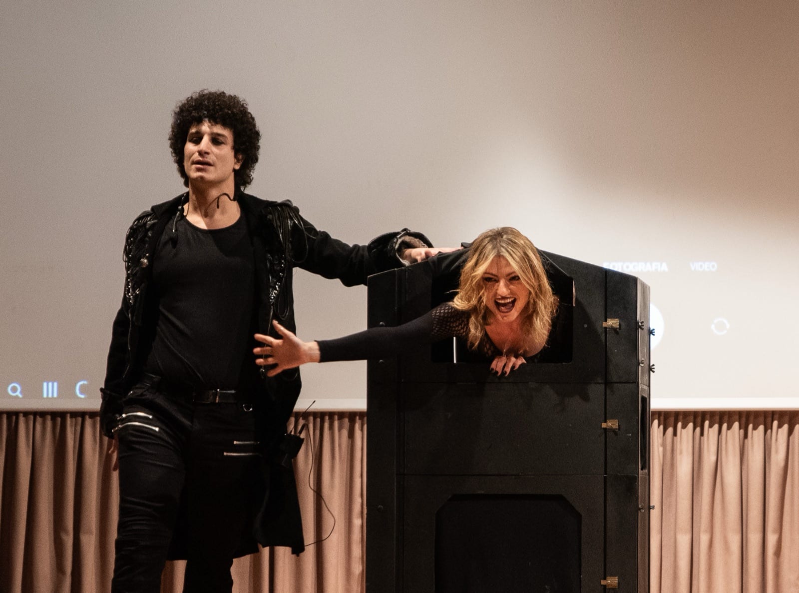 Matteo Angrisano sul palco accanto alla sua assistente, che sporge dalla cassa di una grande illusione